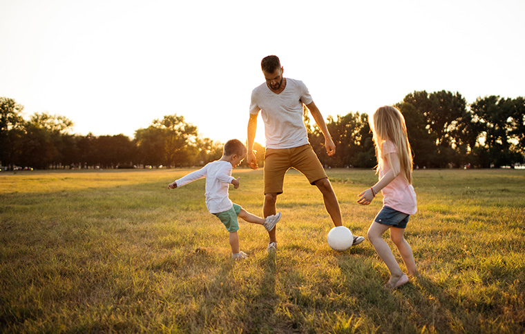 man playing soccer with young children